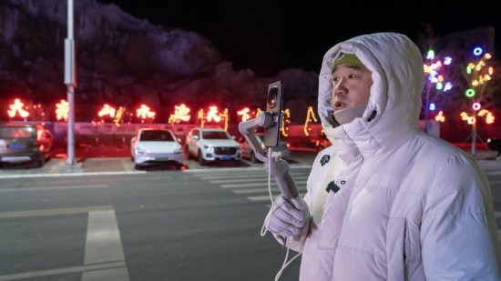 在吉林市阿什哈達霧凇觀景帶，霧凇播報員正在直播。新華社記者 李典 攝