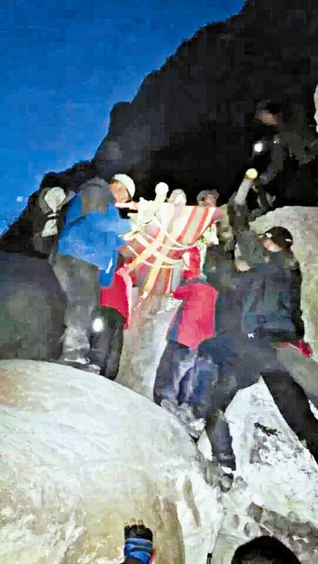 救援隊(duì)員用自制的簡(jiǎn)易擔(dān)架抬傷者。